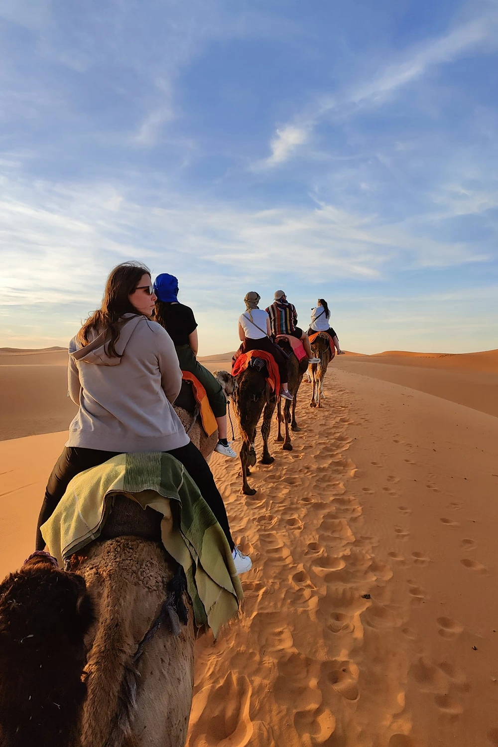 Tourists riding camels through the golden sand dunes of the Sahara Desert near Merzouga